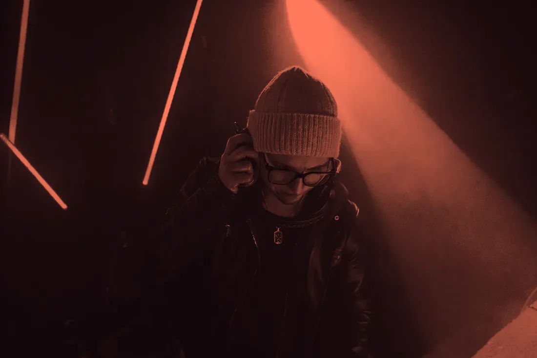 HotStuff mit Beanie und Kopfhörern zwischen roten Neonlinien im Club